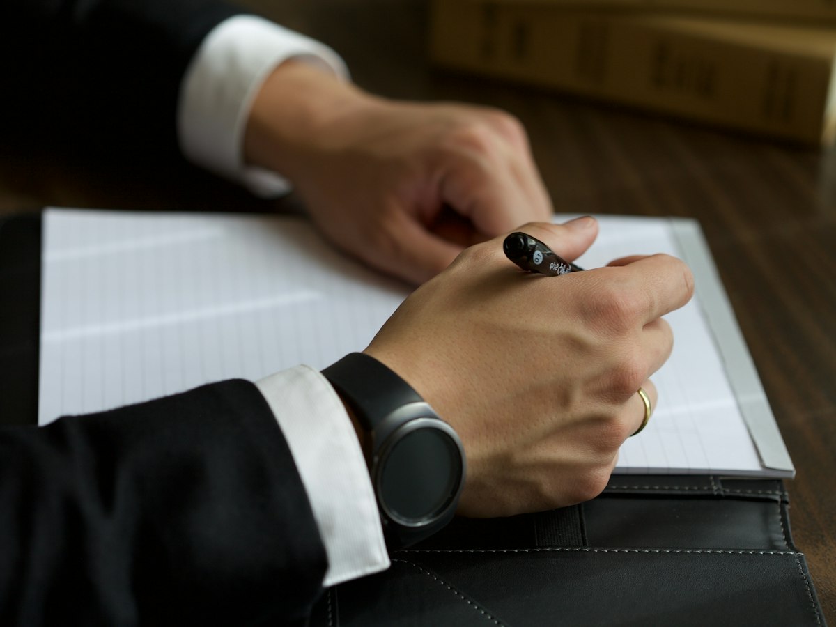 Close-up of hands filling out a legal document on a notepad